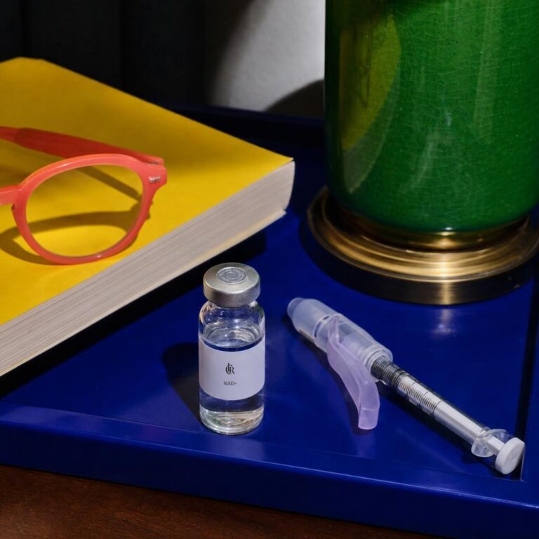 concept clear vial and fully capped safety syringe on a cobalt nightstand tray with reading glasses. Usable package label areas carry a centered, proportion-locked, contrast-appropriate CIRx emblem and approved dose-free identity print; audited unsafe surfaces remain cleanly blank.
