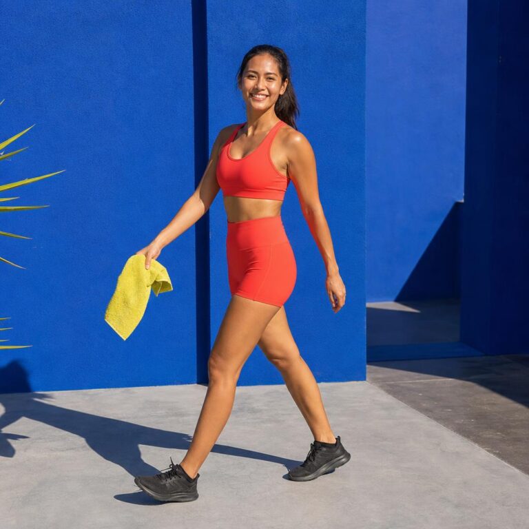 Female model in coral workout clothes carrying a yellow towel, CIRx Athletic V2 campaign